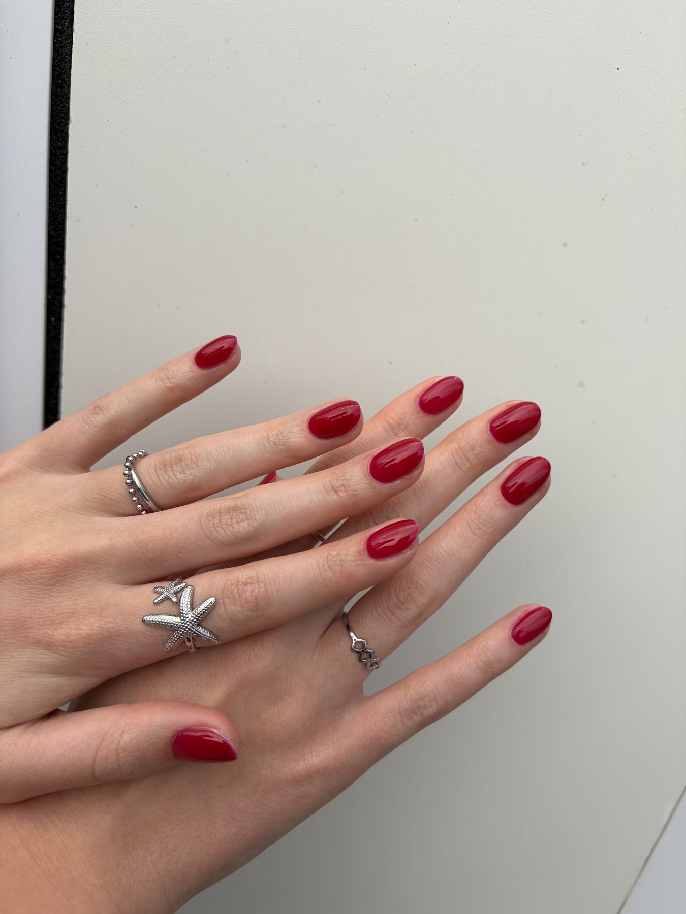 Knalrode nagels, twee handen met zilveren ringen
